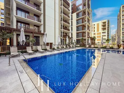 a swimming pool with chairs and umbrellas next to a building at LUX The Orchid Creek Beach Suite in Dubai