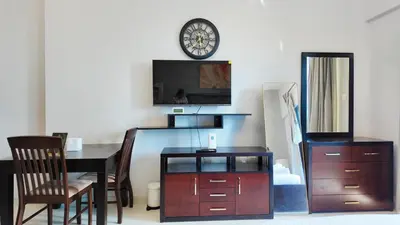 a living room with a table and a clock on the wall at High Floor - Bright Elite Studio in Business Bay in Dubai