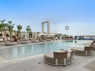 a swimming pool with chairs and a ferris wheel in the background at Spacious Dubai Marina 2BR Great Views Top Location in Dubai