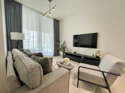 a living room with a couch and a flat screen tv at Brand New Cozy 2br Apartment In Jvc With Balcony in Dubai