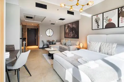 a bedroom with a white bed and a living room at Stylish JLT Studio Lake View PoolMarina Walk in Dubai