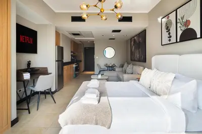 a bedroom with a white bed and a living room at Stylish JLT Studio Lake View PoolMarina Walk in Dubai
