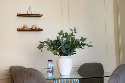 a vase with a plant on a glass table with chairs at Luxe JLT 1BR Apt Gym Pool & Stunning Views in Dubai