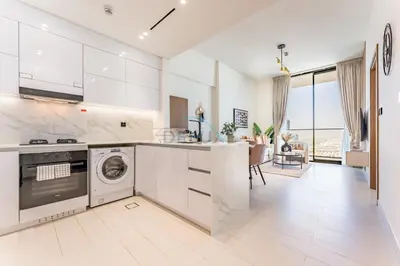 a kitchen with white appliances and a living room at City Views 1BR Near Community Park with Private Balcony, Binghatti House, Jumeirah Village Circle by Deluxe Holiday Homes in Dubai
