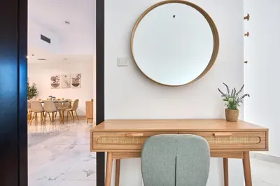 a mirror on a wall next to a table with a chair at Family-Friendly 2BR Apartment in Dubai South at MAG-565 near EXPO and Al Maktoum Airport DWC in Dubai