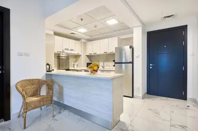 a kitchen with a counter and a chair and a refrigerator at Family-Friendly 2BR Apartment in Dubai South at MAG-565 near EXPO and Al Maktoum Airport DWC in Dubai