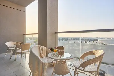 a balcony with tables and chairs and a view of the city at Family-Friendly 2BR Apartment in Dubai South at MAG-565 near EXPO and Al Maktoum Airport DWC in Dubai