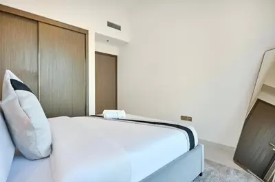 a bedroom with a white bed and a wooden wall at Luxury 2BR Apartment in Grand Bleu Tower at EMAAR Beachfront - High Floor with Marina and City View, Private Beach Access by Stayfinity in Dubai