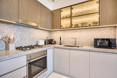 a kitchen with white cabinets and a stove top oven at Luxury 2BR Apartment in Grand Bleu Tower at EMAAR Beachfront - High Floor with Marina and City View, Private Beach Access by Stayfinity in Dubai