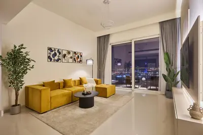 a living room with a yellow couch and a table at Luxury 2BR Apartment in Grand Bleu Tower at EMAAR Beachfront - High Floor with Marina and City View, Private Beach Access by Stayfinity in Dubai