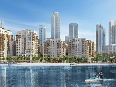 a woman on a paddle board in the water in front of a city at Luxury 2-Bed Retreat with Stunning Creek Views in Dubai