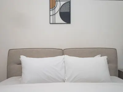 a bed with white pillows and a picture on the wall at Luxury Studio in Peninsula Five, Business Bay in Dubai