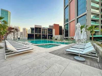 a swimming pool with lounge chairs and a building at Luxury Studio in Peninsula Five, Business Bay in Dubai