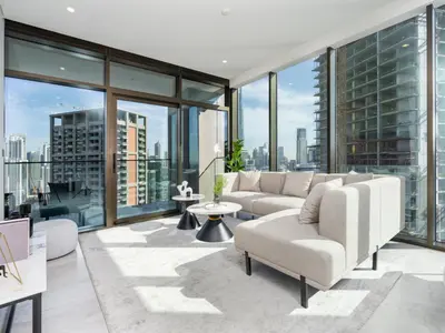 a living room with a couch and chairs and windows at Brand New Business Bay 1 Bed with Burj Khalifa and Canal Views in Dubai
