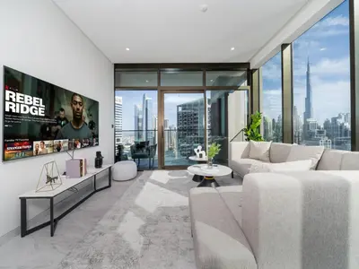 a living room with a white couch and large windows at Brand New Business Bay 1 Bed with Burj Khalifa and Canal Views in Dubai