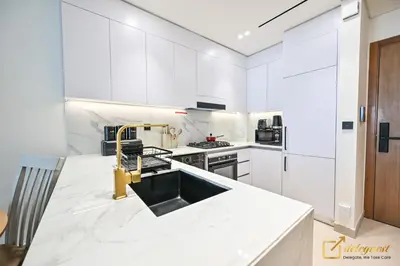a kitchen with white cabinets and a gold sink at Marvelous 1BR in Binghati Amber by deleguest in Dubai