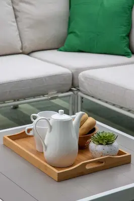 a tea kettle on a wooden tray on a table with a couch at Frank Porter - Serenity Lakes 5 in Dubai