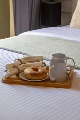a tray with a donut and a cup on a bed at Frank Porter - Rokane G22 in Dubai