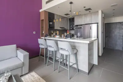 a kitchen with purple walls and a bar with stools at Frank Porter - MBL Royal in Dubai