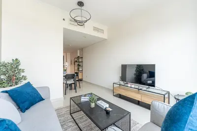 a living room with a couch and a tv at HAVN - 1 Bed in Damac Hills 1, Golf Course View in Dubai