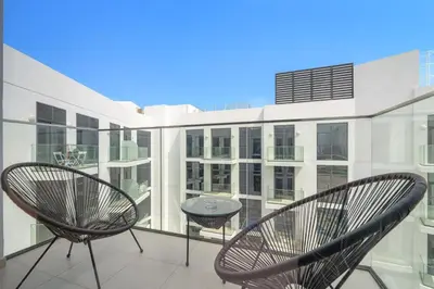 a balcony with two chairs and a table on a building at Silkhaus Stylish 2BDR in Azizi Gardens with Pool & Gym in Dubai