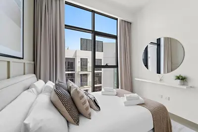 a white bedroom with a large window and a white couch at Silkhaus Stylish 2BDR in Azizi Gardens with Pool & Gym in Dubai