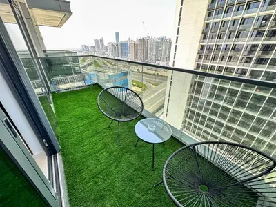 a balcony with two chairs and a table on the grass at Vserve I 1 BR - Luxury Escape in Business Bay in Dubai