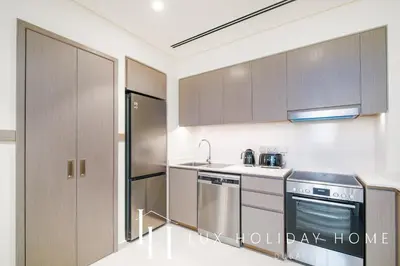 a kitchen with stainless steel appliances and wooden cabinets at LUX The Grande Signature Skyline Suite in Dubai
