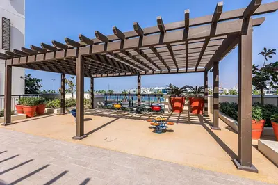 a wooden pergola with orange chairs on a patio at Elite LUX Holiday Homes - 1BHK Beachside Retreat at Port De La Mer, Dubai in Dubai