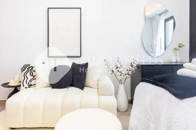 a bedroom with a white couch and a mirror at Bloomfields Modern Escape STU In JVC in Dubai