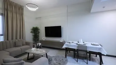 a living room with a table and a tv at 2 Bedroom Elegant Apartment in Dubailand in Dubai