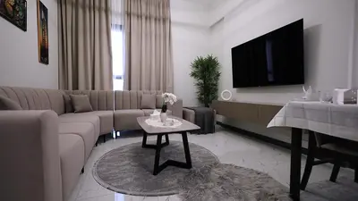a living room with a couch and a tv at 2 Bedroom Elegant Apartment in Dubailand in Dubai