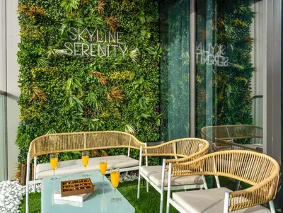 a patio with a green wall with a table and chairs at Grande Signature 2 Bedroom Apartments I Persian Gulf Views I Free Parking, Gym, Pool, Wi-Fi & PS5 I by Skyline Serenity in Dubai