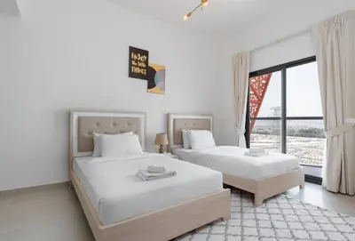 two beds in a white room with a window at Delightful 2 Bedrooms In Jumeirah Village Circle in Dubai