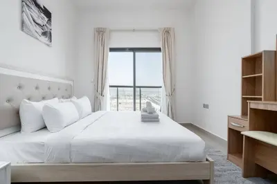 a bedroom with a white bed with a large window at Delightful 2 Bedrooms In Jumeirah Village Circle in Dubai