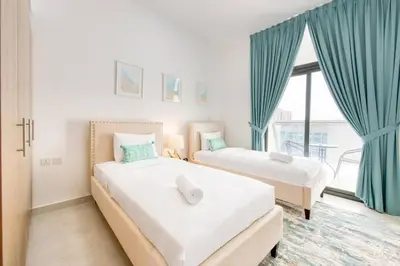 two beds in a room with blue curtains and a window at Serene 2 Bedrooms Apartment in Dubai