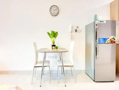 a table and chairs in a kitchen with a refrigerator at Posh Studio Apartments in Dubai