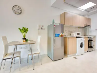 a kitchen with a table and chairs and a refrigerator at Posh Studio Apartments in Dubai