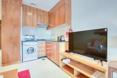 a kitchen with a tv and a washing machine at Restful studio Apartment in Dubai Sports City in Dubai