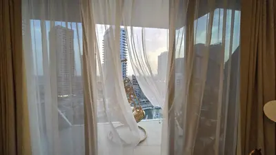 a window with white curtains and a view of a city at Stella Maris Marine view in Dubai