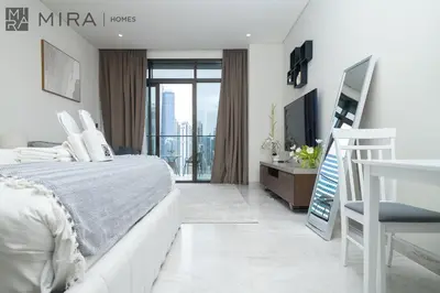 a white bedroom with a bed and a television at Mira Holiday Homes - newly and cosy studio with balcony in Business Bay in Dubai