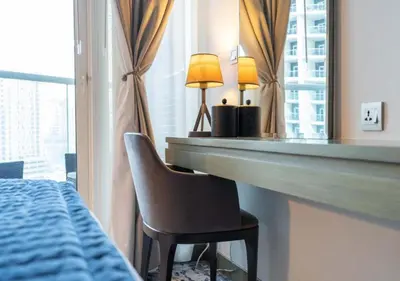 a bedroom with a desk and a bed and a mirror at Bespoke Holiday Homes - Luxurious Studio in Damac Maison Prive in Dubai