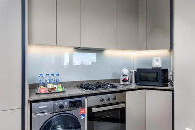 a kitchen with a washing machine and a microwave at Waves - Elegant Waterfront Living in Dubai's Business Bay in Dubai