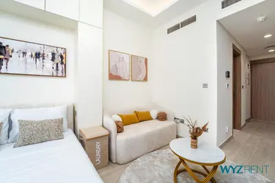 a living room with a couch and a table at Winter Bliss Studio Azizi Riviera 9 Pool View in Dubai