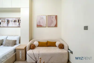 a living room with a couch and two pictures on the wall at Winter Bliss Studio Azizi Riviera 9 Pool View in Dubai