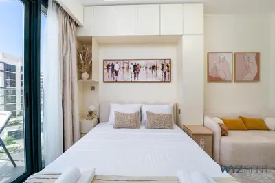 a bedroom with a large white bed and a couch at Winter Bliss Studio Azizi Riviera 9 Pool View in Dubai