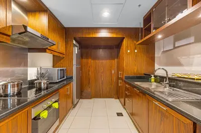 a kitchen with wooden cabinets and stainless steel appliances at Durrani Homes - Modern Living 3br with Burj Khalifa and Fountain View - third room without partition in Dubai
