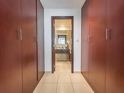 a hallway with three wooden doors and a bathroom at The Cozy Cove 1BR at Rimal 4,JBR in Dubai