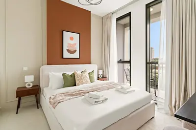 a white bedroom with a large bed and a window at Silkhaus Signature 1BR in Afnan at Production City in Dubai