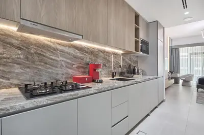 a kitchen with white cabinets and a red stove at Lux High-Rise Studio 12th Floor Westwood Grande in Dubai